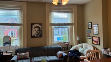 Living room with couch in front of windows with prints on the walls.