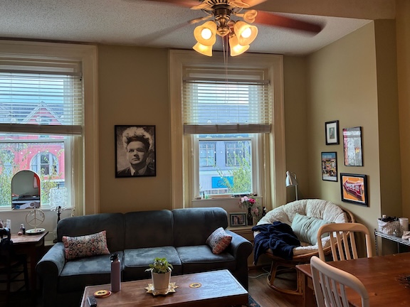 Living room with couch in front of windows with prints on the walls. 