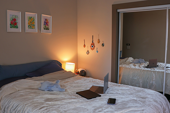 A wide shot of an apartment bedroom with subtle lighting and decorations. 