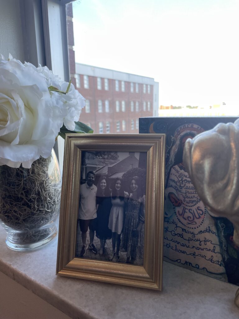 A family photo of Randall, her sister and her mother and father sits beside faux flowers in Julia's windowsill. 