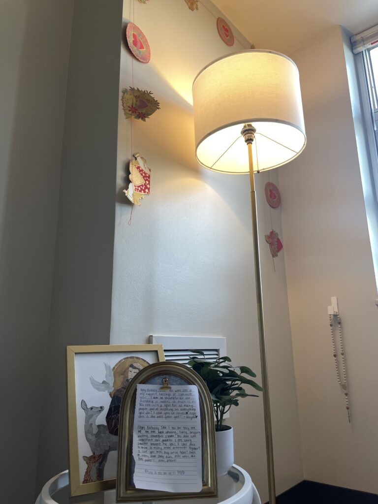 A rosary and a garland of sacred heart images hang in the corner of Julia Randall's room in Brumby Hall. The corner is a quiet space for faith.