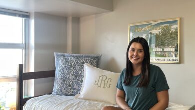 Julia Randall sits on her lofted bed in her room in Brumby Hall. Randall's room is decorated with cream and blue tones and keeps her blinds open.