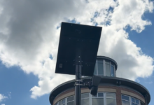 A flock safety camera against the sky with clouds