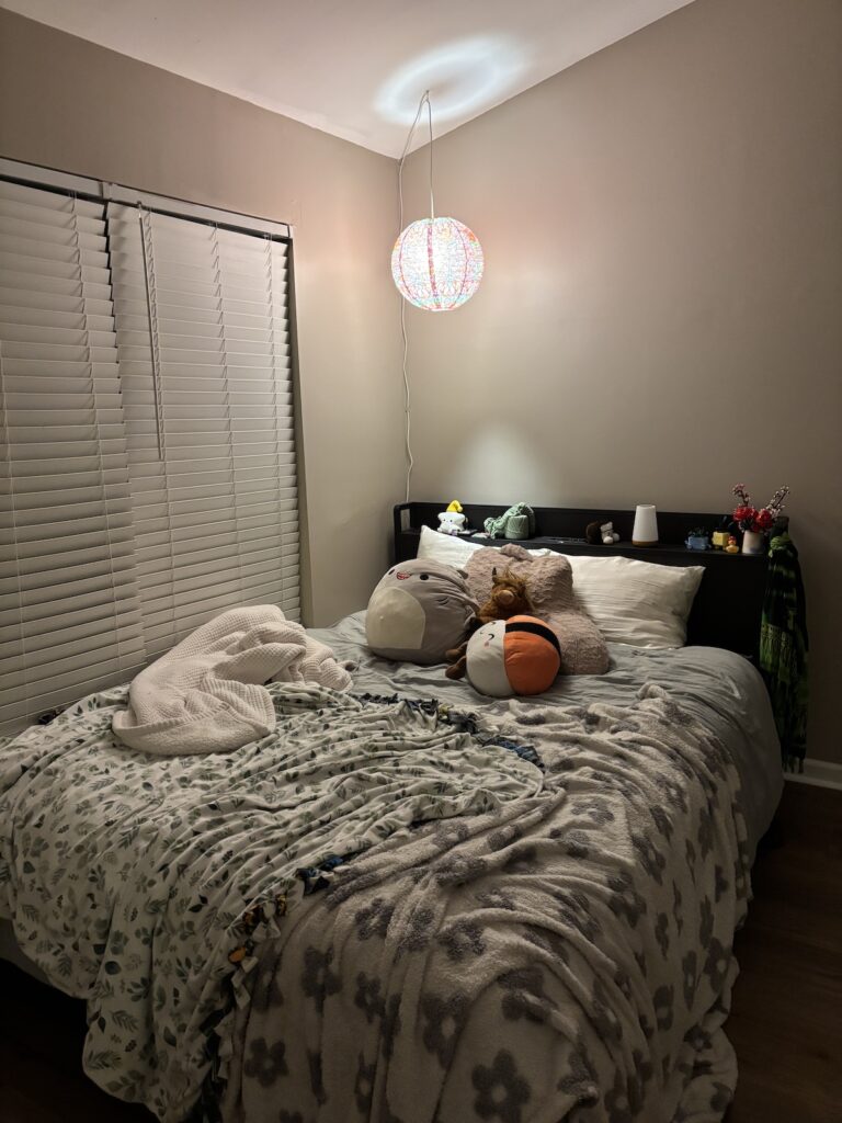 A bed in the corner of a room with stuffed animals and blankets.
