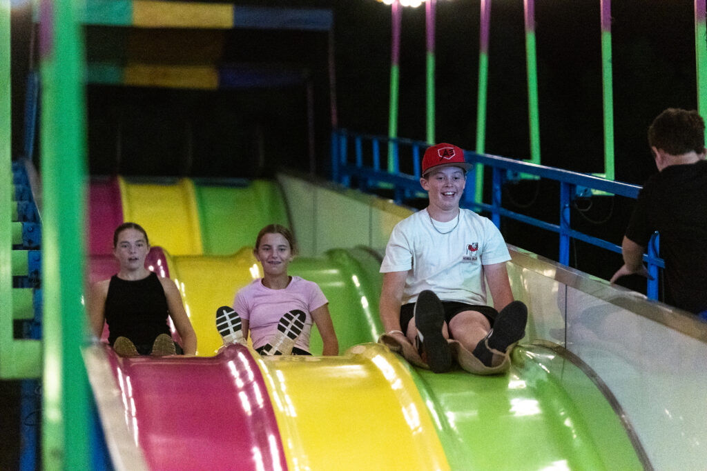 three people go down colorful slides