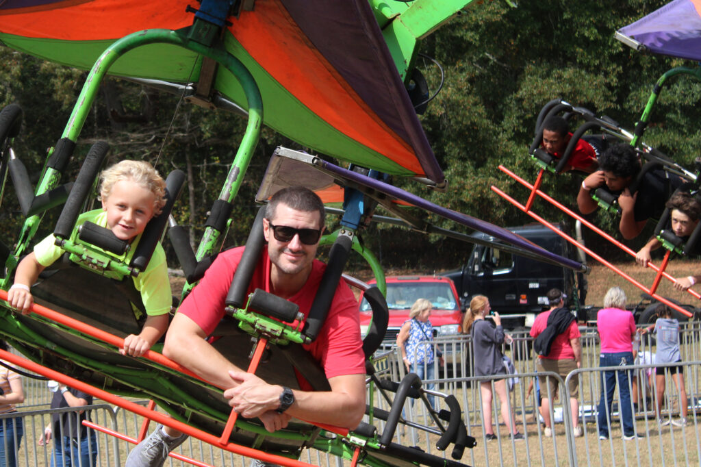 Two people are seen on a carnival ride that is colorful