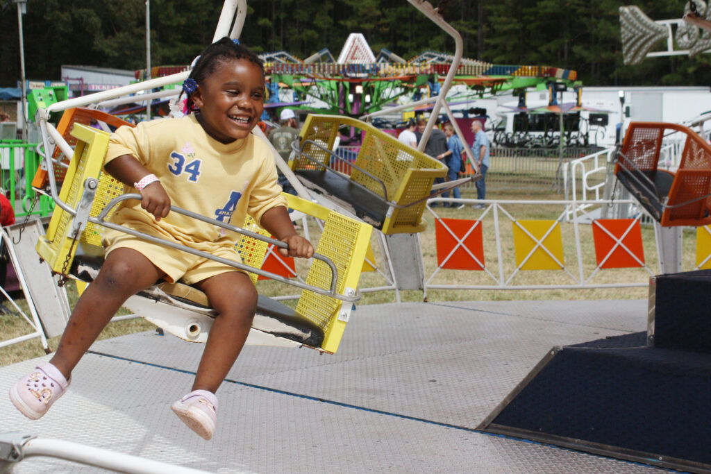 A child smiles while on a swing ride at the fair