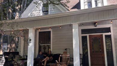 Two people sit on the front porch of a home