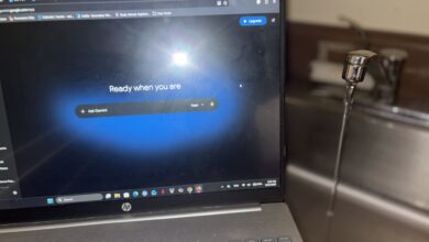A laptop displays Google Gemini's homepage while a faucet runs water in the background.