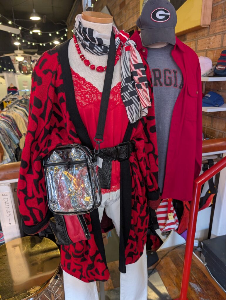 Two mannequin displays sit at the entrance of Dynamite Clothing in red and black apparel; one being driven for female customers and the other for male customers. They include accessories like clear bags and necklaces, while also being pieces that can be worn outside of game day.